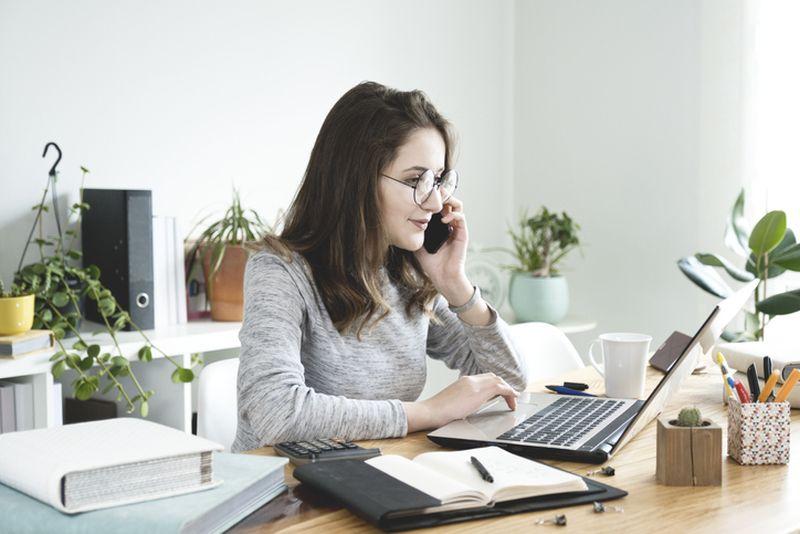 kobieta rozmawiająca przez telefon i korzystająca z laptopa